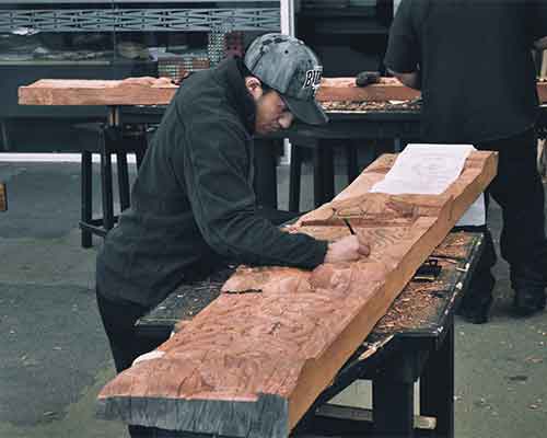 Woodworker marking out a timber beam on a workshop bench